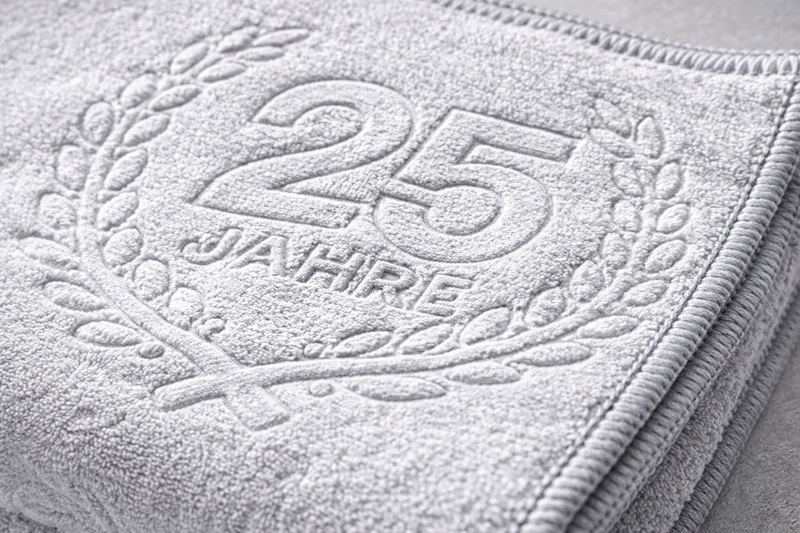 Detailaufnahme eines grauen Geschirrtuchs aus dem 6er Set mit geprägtem 25 Jahre Motiv