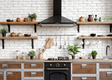 Moderne Küche mit schwarzer Dunstabzugshaube über dem Herd, sauberen Regalen und gepflegten Arbeitsflächen als Teaserbild zum Thema Dunstabzugshaube reinigen und Fett entfernen in der Küche