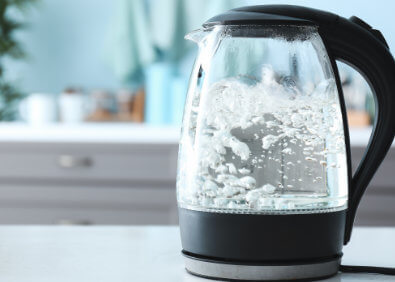 Glas-Wasserkocher mit kochendem Wasser in moderner Küche als Teaserbild zum Thema Entkalken und Entfernen von Kalkablagerungen