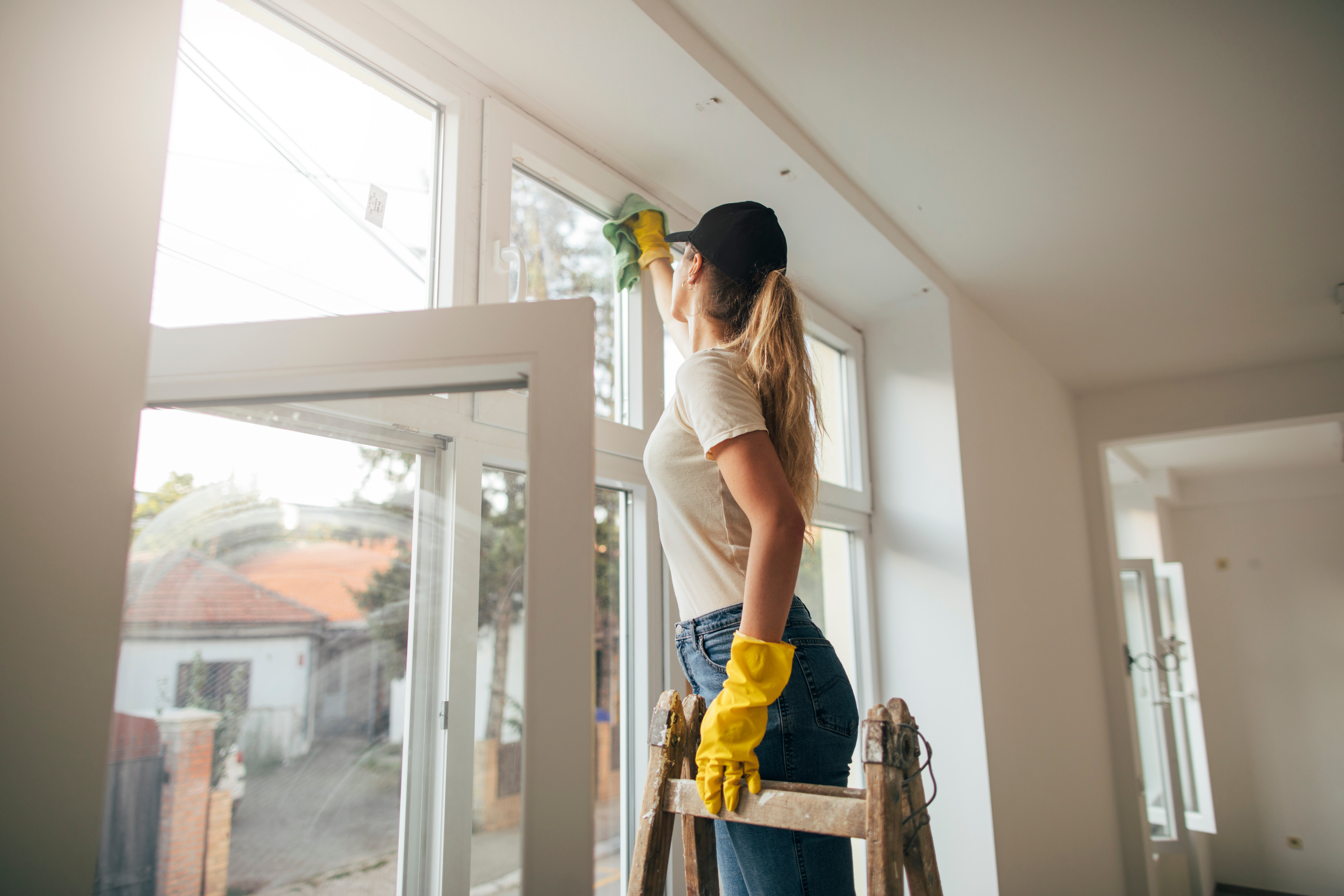Eine Frau auf einer Leiter beim Fensterputzen