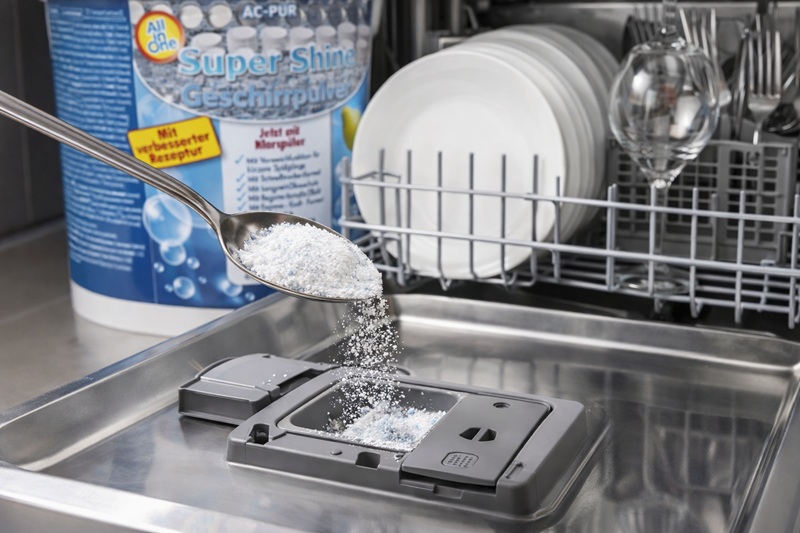 AC PUR Super Shine Geschirrpulver wird mit einem Teelöffel in das Dosierfach der Spülmaschine gegeben.