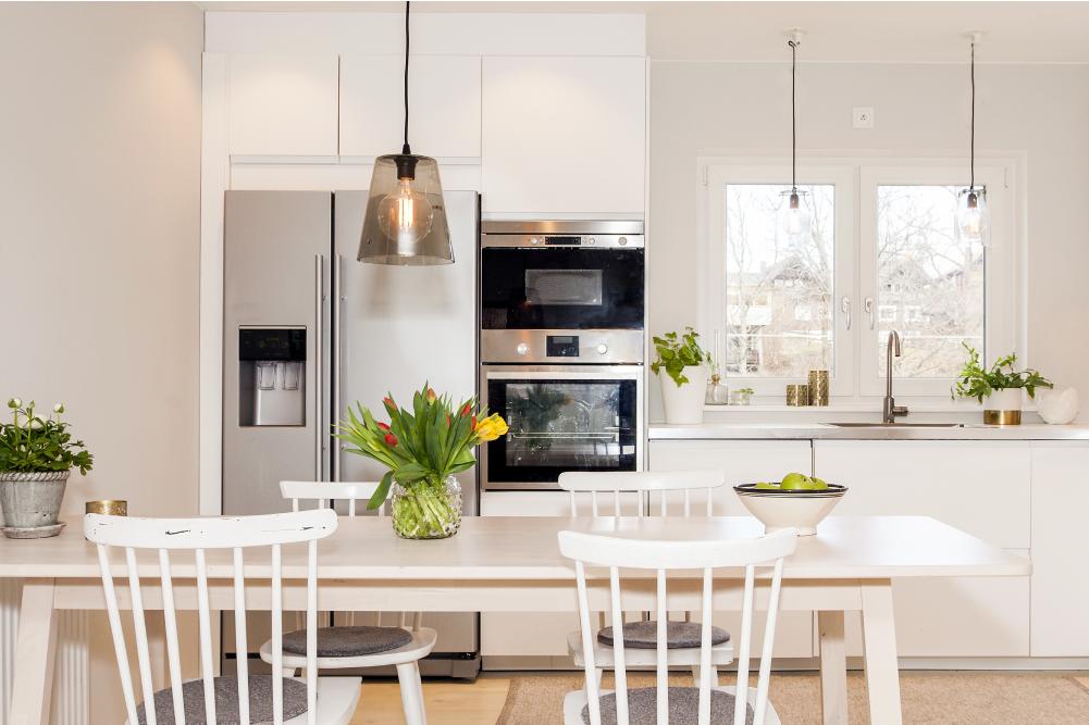 Helle moderne Küche mit Esstisch, weißen Möbeln und gepflegten Oberflächen als Teaserbild zum Thema Frühjahrsputz und gründliche Haushaltsreinigung