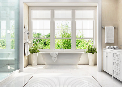 Helles modernes Badezimmer mit Badewanne, großen Fenstern, weißen Fliesen und Waschschrank als Teaserbild zum Thema Bad reinigen und putzen